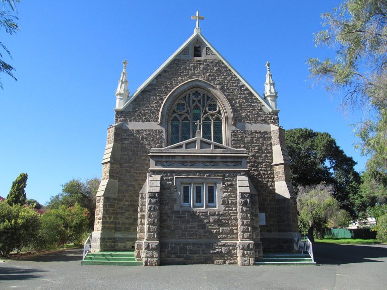 A small clock tower in front of a brick building