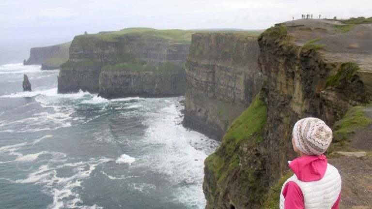 A girl standing on a rock with Cliffs of Moher in the background